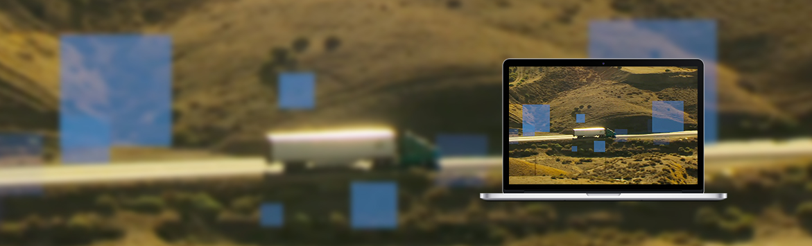 A banner image of a laptop screen featuring truck travelling along a highway surrounded by grass fields.